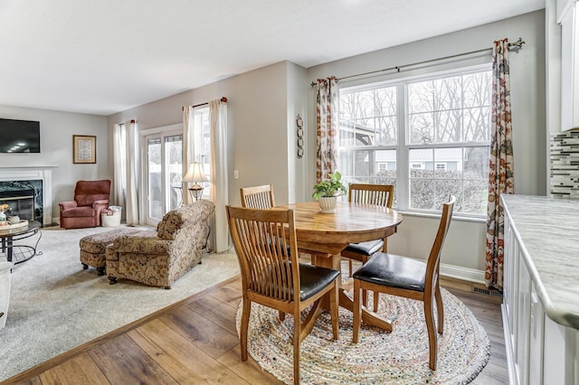 dining area with plenty of natural light, light hardwood / wood-style floors, and a premium fireplace