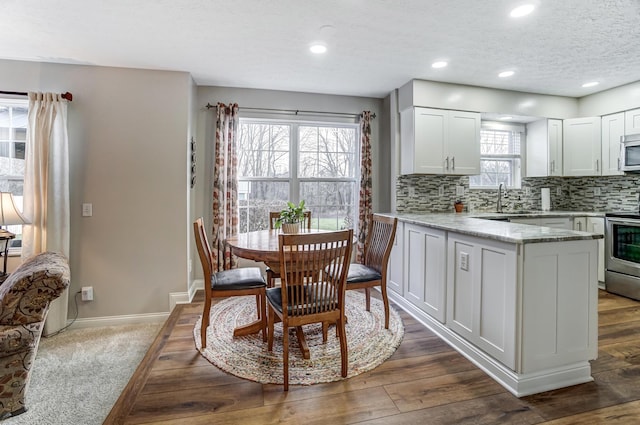 kitchen featuring white cabinets, decorative backsplash, light stone countertops, and stainless steel appliances