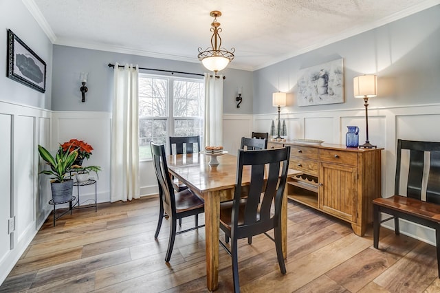 dining area with ornamental molding, a textured ceiling, and light hardwood / wood-style flooring