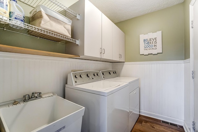 laundry room featuring sink, cabinets, washing machine and dryer, dark hardwood / wood-style flooring, and a textured ceiling