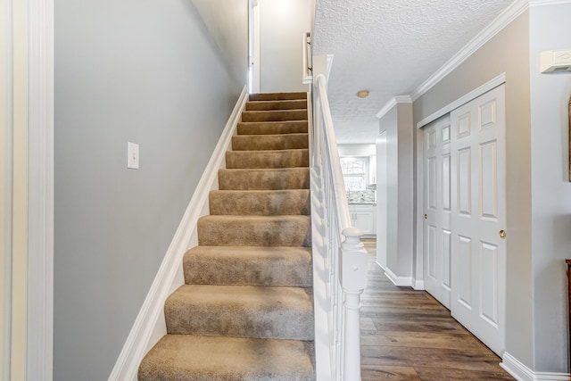 stairs featuring hardwood / wood-style floors, ornamental molding, and a textured ceiling