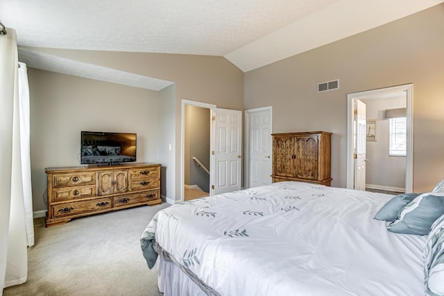 carpeted bedroom featuring ensuite bathroom and lofted ceiling