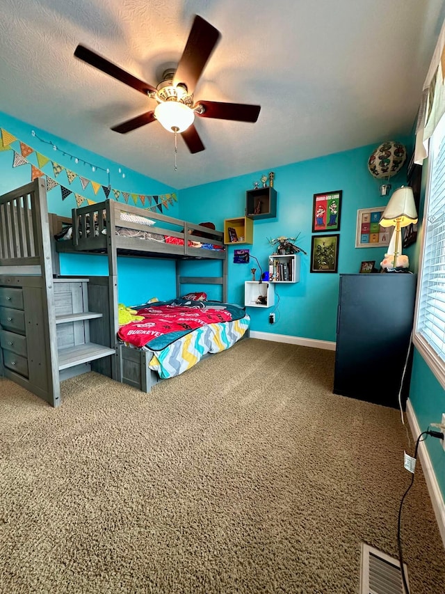 carpeted bedroom with ceiling fan and a textured ceiling