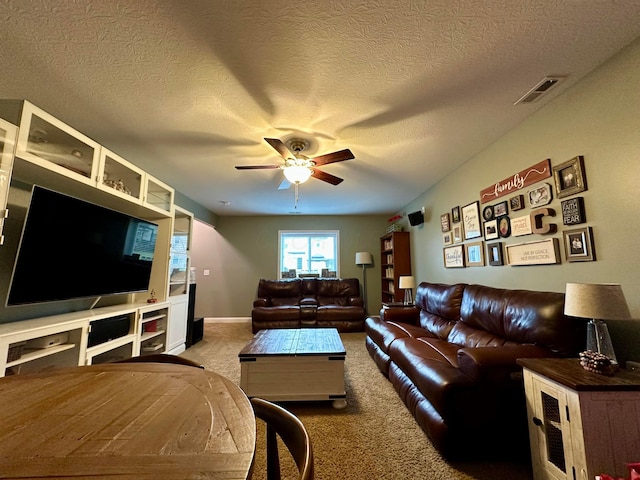 carpeted living room featuring ceiling fan and a textured ceiling