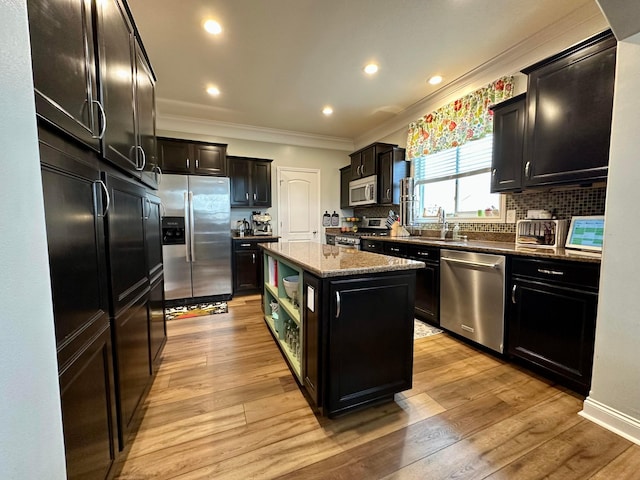 kitchen featuring dark stone countertops, a center island, stainless steel appliances, and light hardwood / wood-style flooring