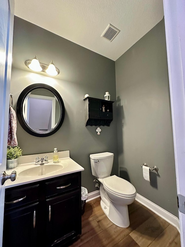 bathroom featuring hardwood / wood-style flooring, vanity, toilet, and a textured ceiling