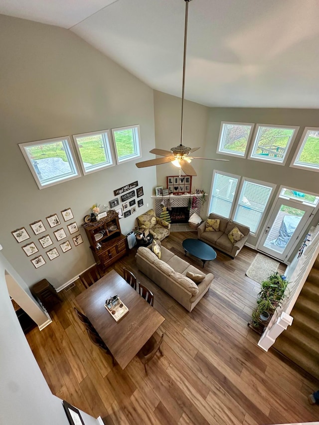 living room with ceiling fan, a fireplace, high vaulted ceiling, and hardwood / wood-style floors