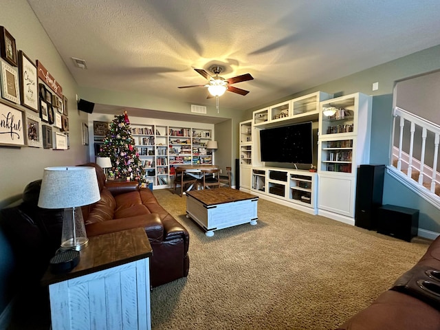 carpeted living room with ceiling fan, a textured ceiling, and built in shelves