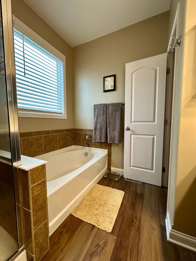 bathroom with hardwood / wood-style floors and shower with separate bathtub