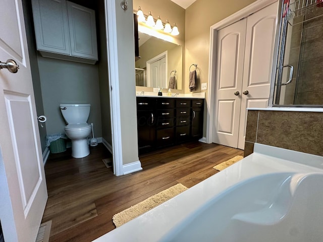 bathroom with hardwood / wood-style floors, vanity, a shower with shower door, and toilet