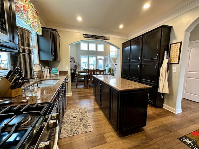 kitchen with stone countertops, a kitchen island, range with two ovens, and sink