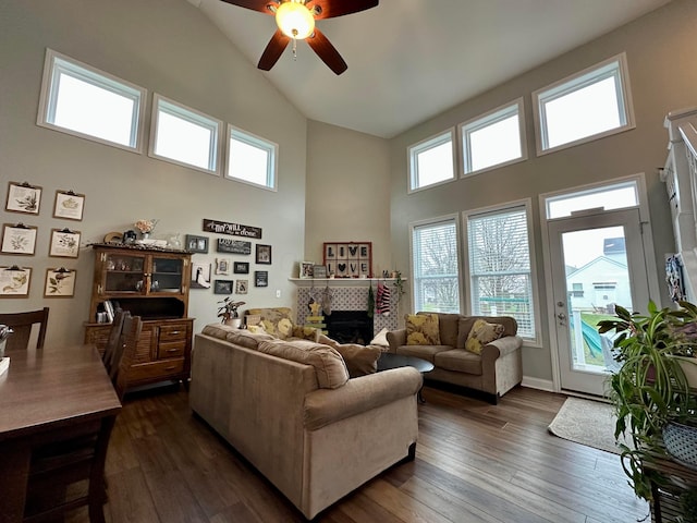 living room with a tile fireplace, ceiling fan, dark hardwood / wood-style flooring, and high vaulted ceiling