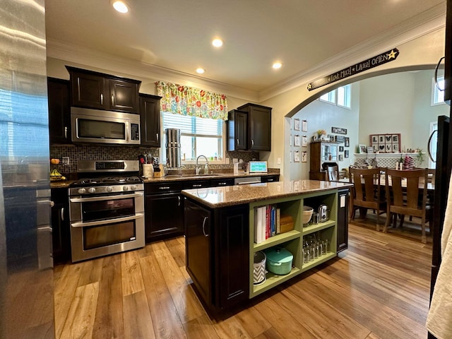 kitchen with light wood-type flooring, a center island, stainless steel appliances, and dark stone counters