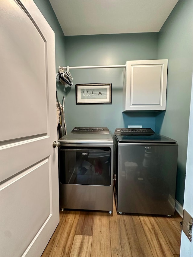 laundry area featuring cabinets, light wood-type flooring, and separate washer and dryer