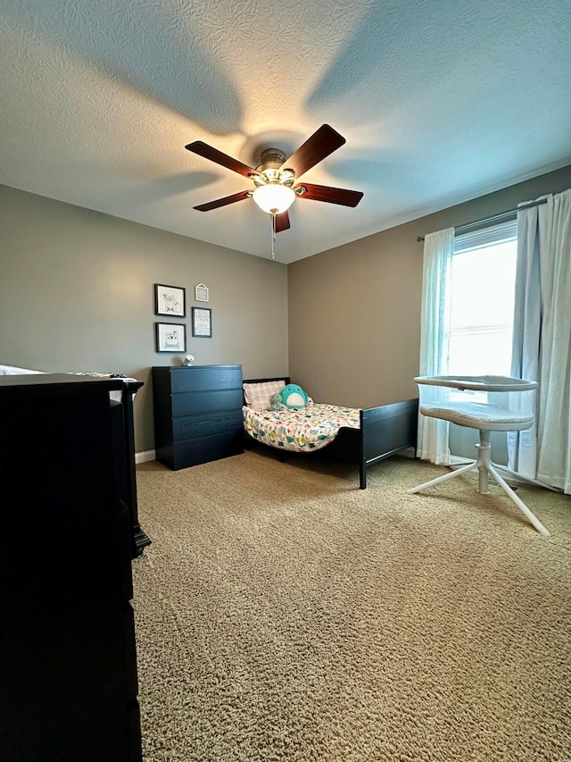 bedroom with ceiling fan, carpet floors, and a textured ceiling