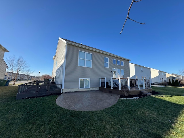 rear view of property featuring a lawn, a patio area, and a deck