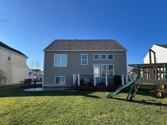 rear view of house featuring a lawn, a deck, and a playground