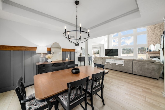 dining space featuring plenty of natural light, light hardwood / wood-style flooring, an inviting chandelier, and a tray ceiling