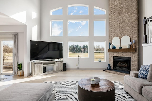 living room featuring light wood-type flooring, a fireplace, and a high ceiling