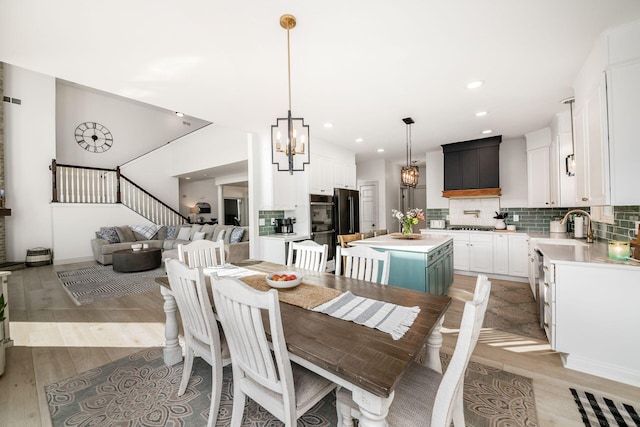 dining area with an inviting chandelier, sink, and light hardwood / wood-style flooring