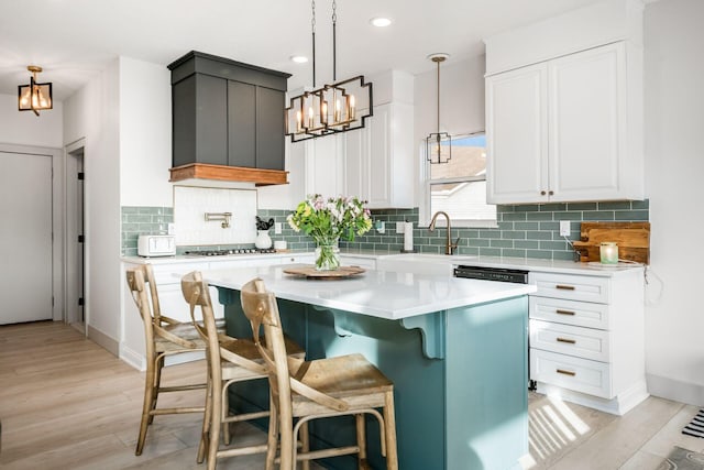 kitchen featuring sink, a breakfast bar area, white cabinetry, hanging light fixtures, and a center island