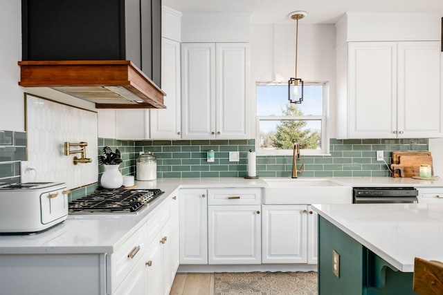 kitchen with black dishwasher, white cabinets, hanging light fixtures, stainless steel gas cooktop, and custom range hood