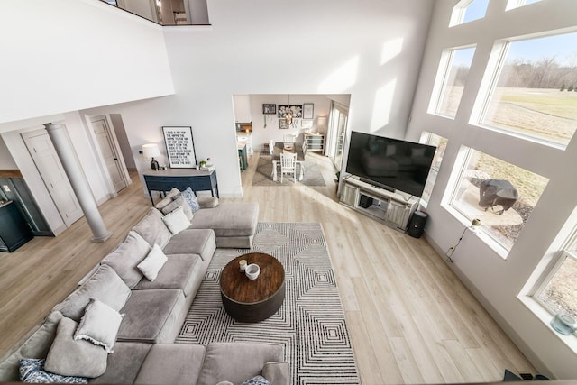 living room featuring a towering ceiling and light hardwood / wood-style flooring