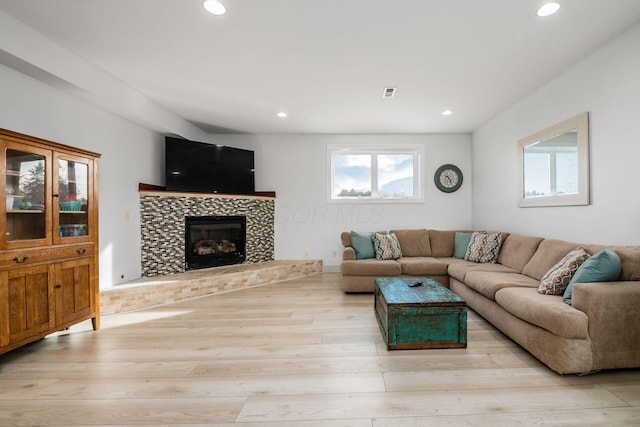 living room with a tiled fireplace and light hardwood / wood-style floors