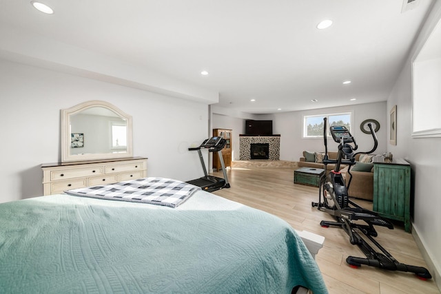 bedroom with a tiled fireplace and light wood-type flooring