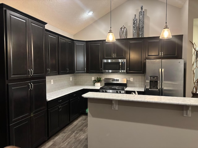 kitchen with decorative light fixtures, tasteful backsplash, lofted ceiling, stainless steel appliances, and dark wood-type flooring