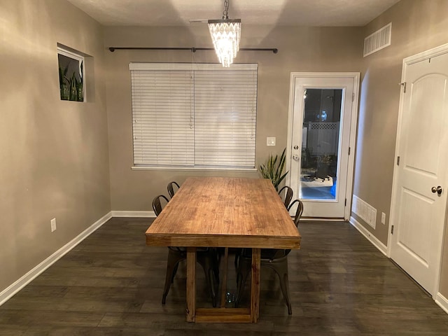 dining room with dark hardwood / wood-style floors and a chandelier