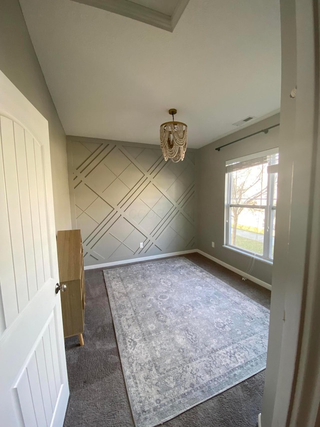 empty room featuring an inviting chandelier and dark carpet