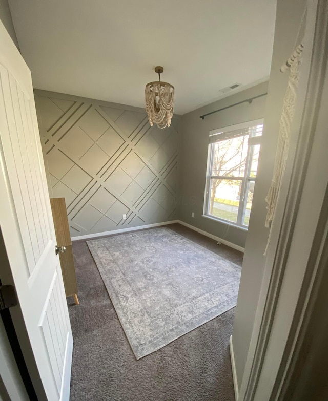 unfurnished dining area with a chandelier and dark colored carpet