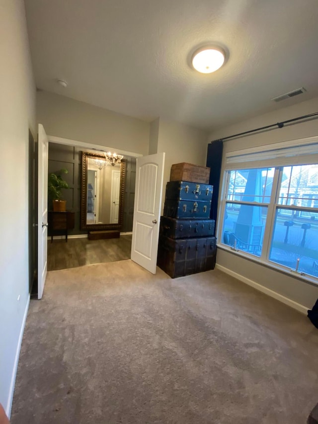 unfurnished bedroom with an inviting chandelier and carpet floors