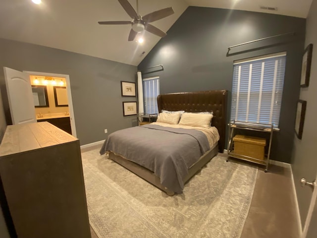 bedroom with ceiling fan, connected bathroom, light colored carpet, and high vaulted ceiling