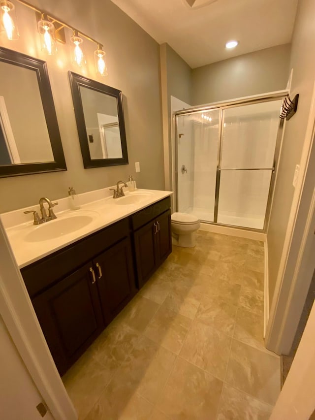 bathroom featuring vanity, a shower with shower door, and toilet