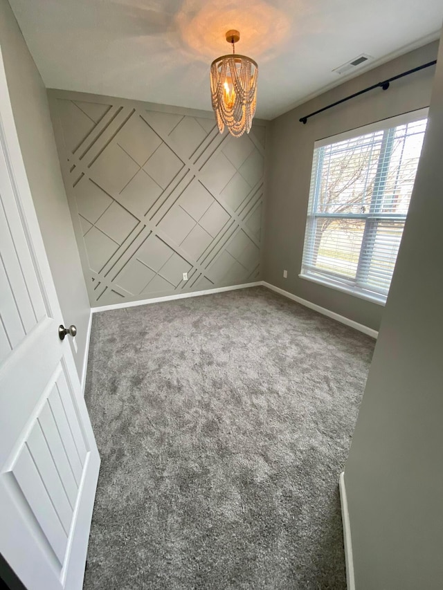 carpeted empty room with a notable chandelier