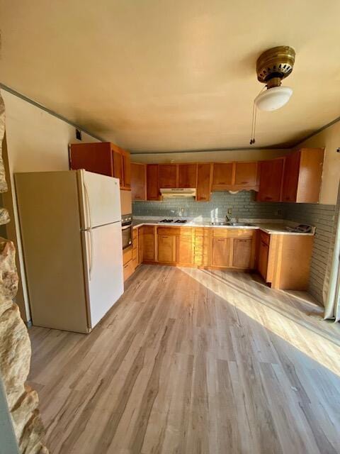 kitchen featuring sink, gas stovetop, wall oven, white fridge, and light hardwood / wood-style floors