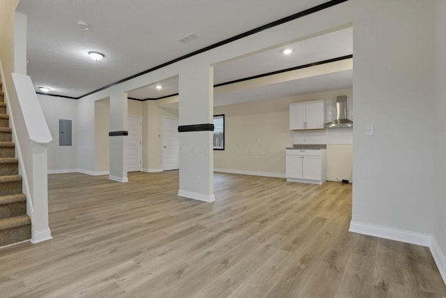 unfurnished living room with electric panel, crown molding, and light wood-type flooring