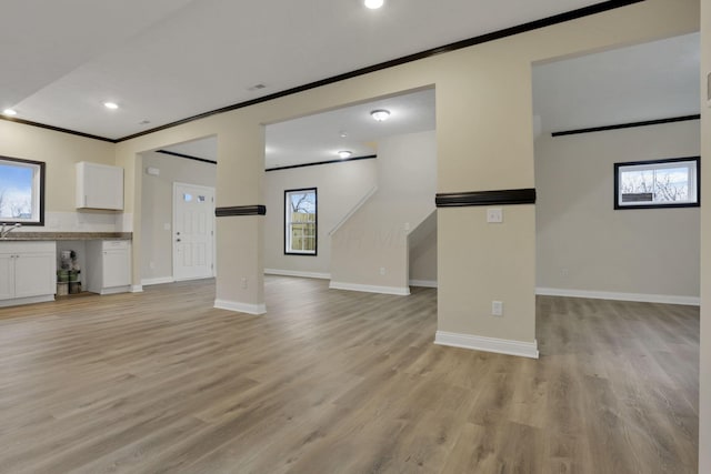 unfurnished living room with crown molding and light hardwood / wood-style floors