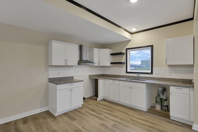 kitchen featuring white cabinets, wall chimney exhaust hood, light wood-type flooring, and sink