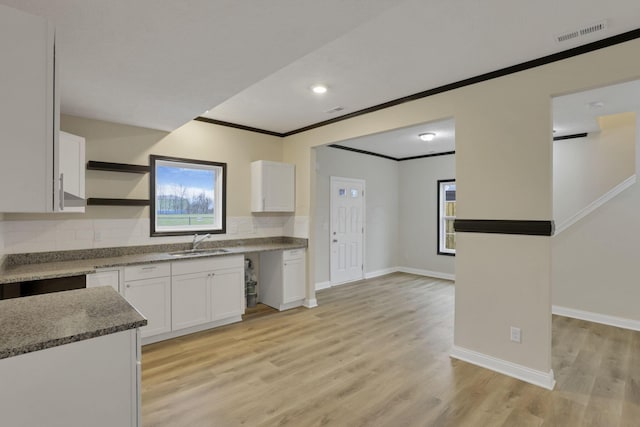 kitchen with white cabinets, light hardwood / wood-style flooring, crown molding, and sink