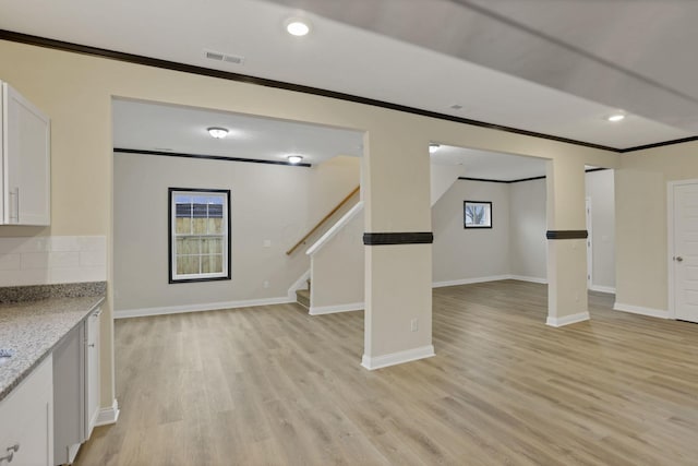 basement with crown molding and light hardwood / wood-style flooring