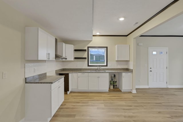 kitchen with white cabinets, light wood-type flooring, tasteful backsplash, and sink