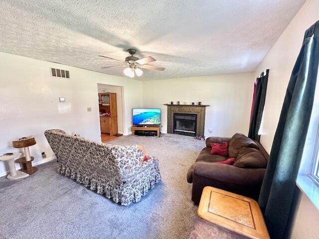 living room featuring a textured ceiling, carpet floors, and ceiling fan