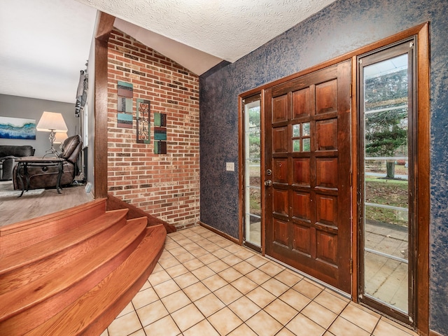 tiled foyer with a textured ceiling, a healthy amount of sunlight, and lofted ceiling