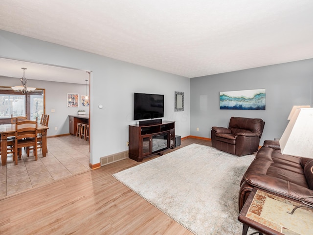 living room with light hardwood / wood-style flooring and an inviting chandelier