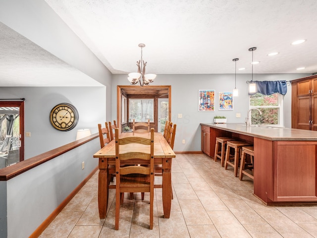 tiled dining area featuring a textured ceiling, an inviting chandelier, and sink