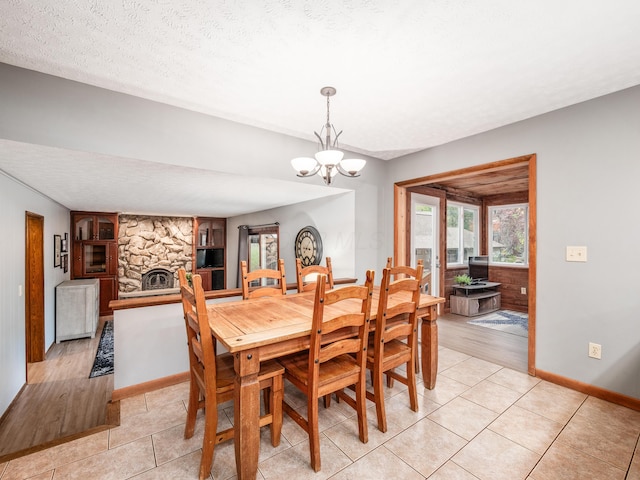 dining area featuring a fireplace, light tile patterned floors, a textured ceiling, and a notable chandelier