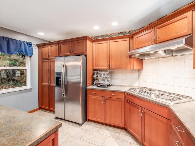 kitchen featuring backsplash, light tile patterned flooring, and stainless steel appliances